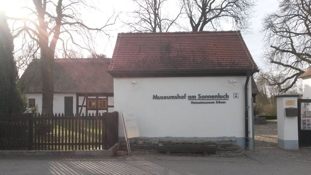 Außenansicht. Altes Bauernhaus mit weißer Fassade. Aufschrift am Haus "Museumshof am Sonnenlurch. Heimatmuseum Erkner".