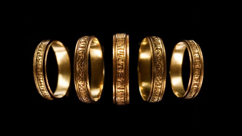 Vor einem schwarzen Hintergrund werden fünf goldene Ringe gezeigt.